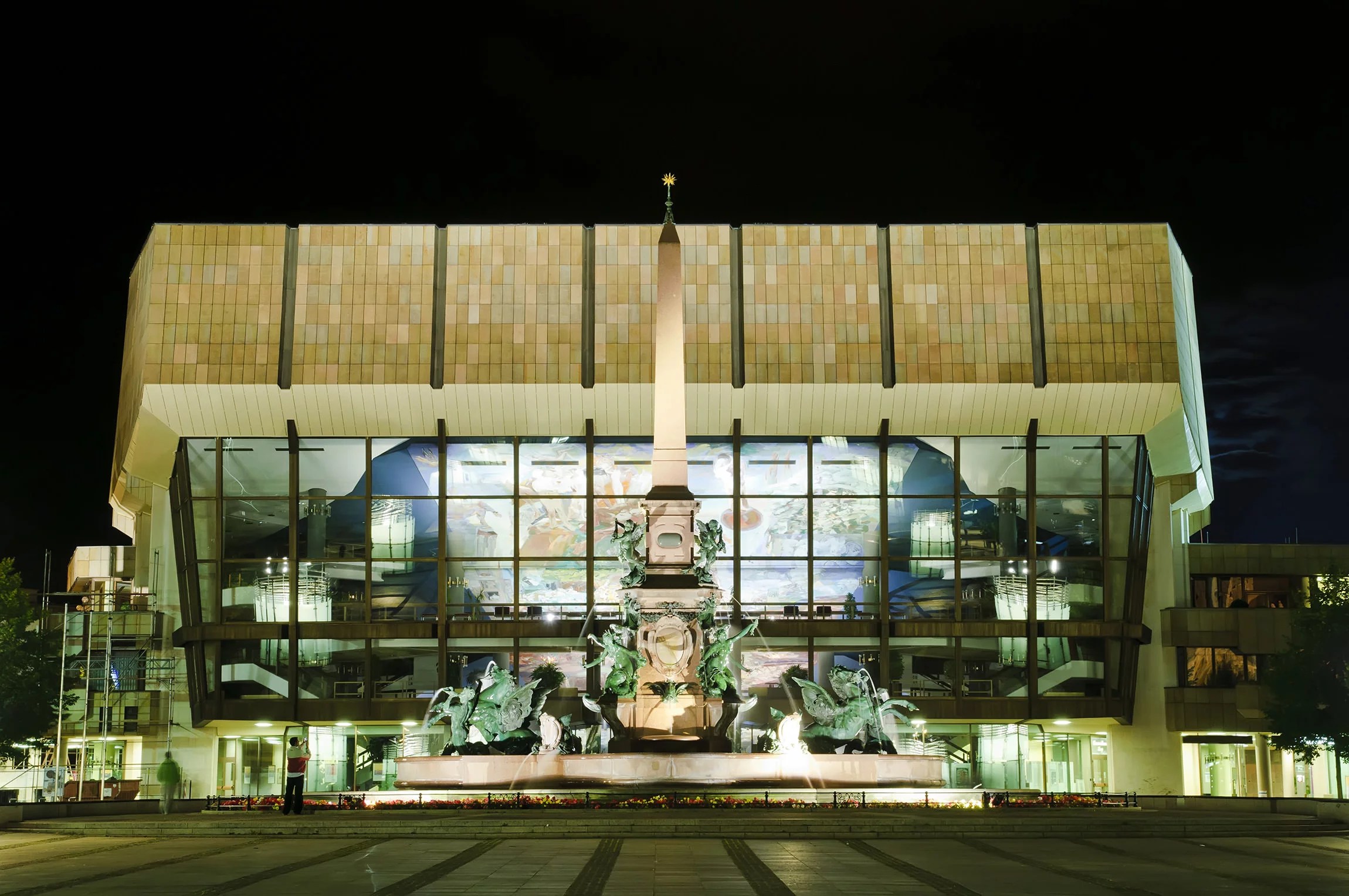 Neo-Baroque Mende fountain in front of the 80ies concrete block on the Augustusplatz square